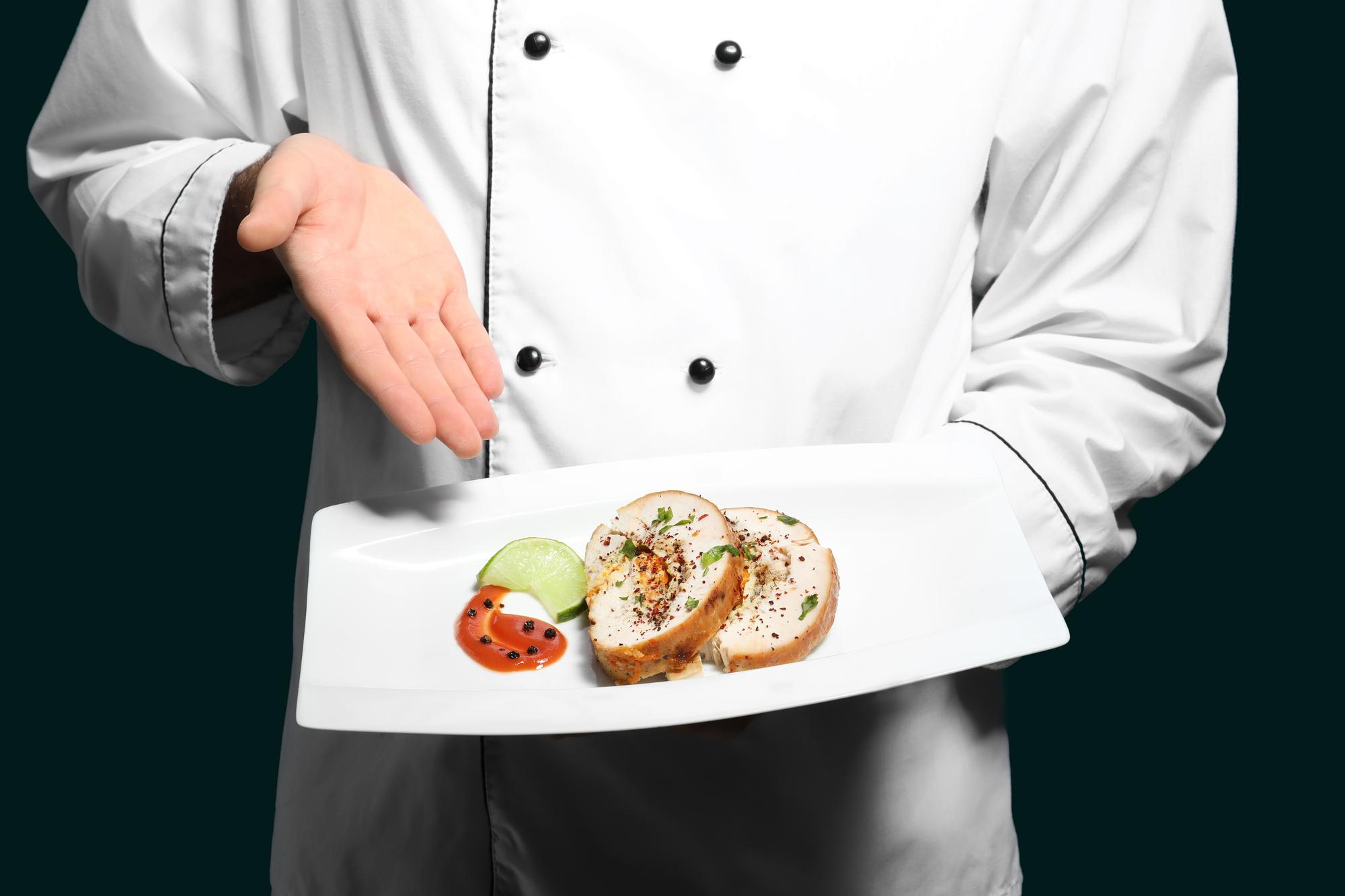 chef arranging plated tasting menu on white ceramic